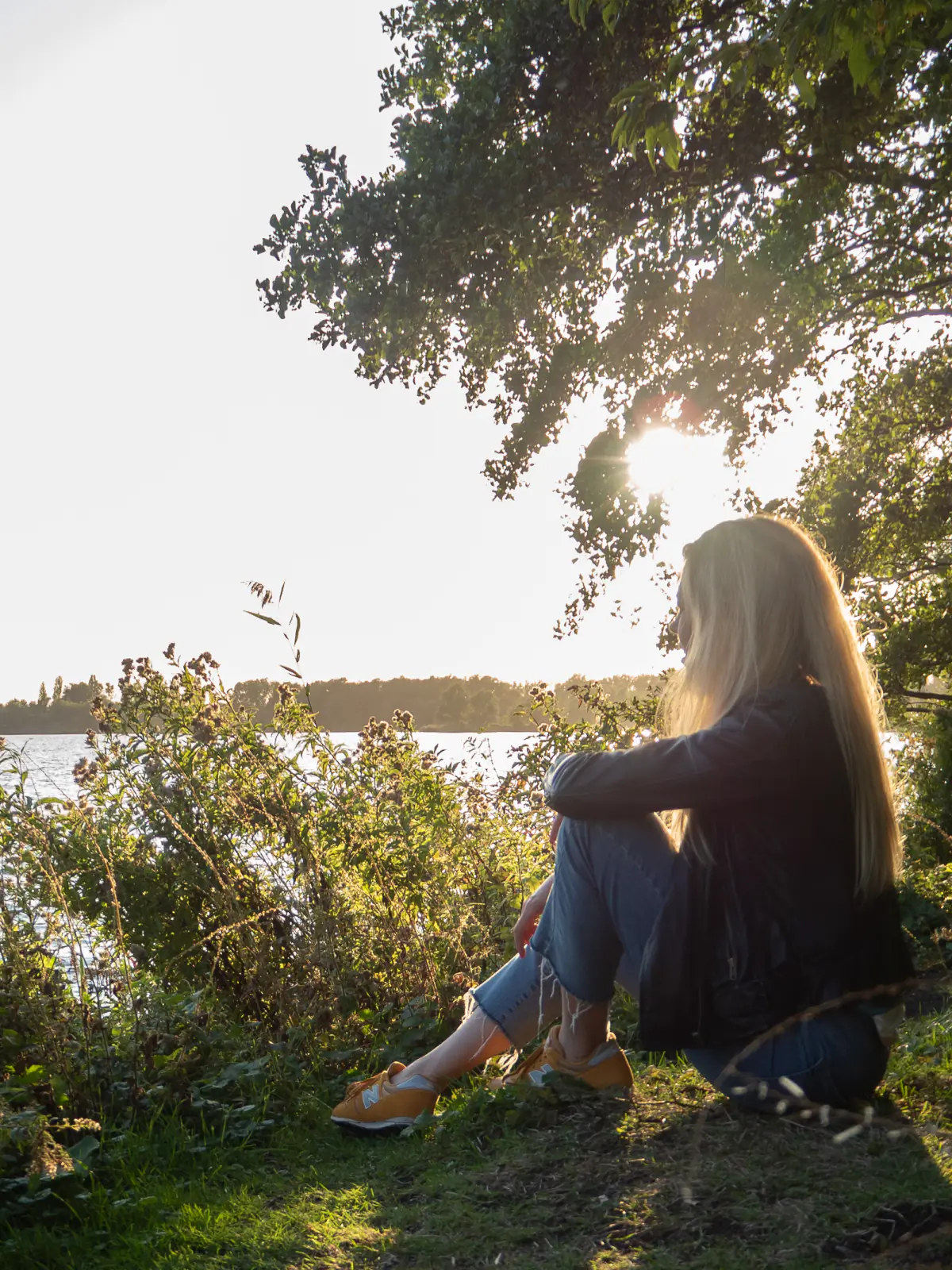 Anneke zit aan de oever van het meer in het tegenlicht